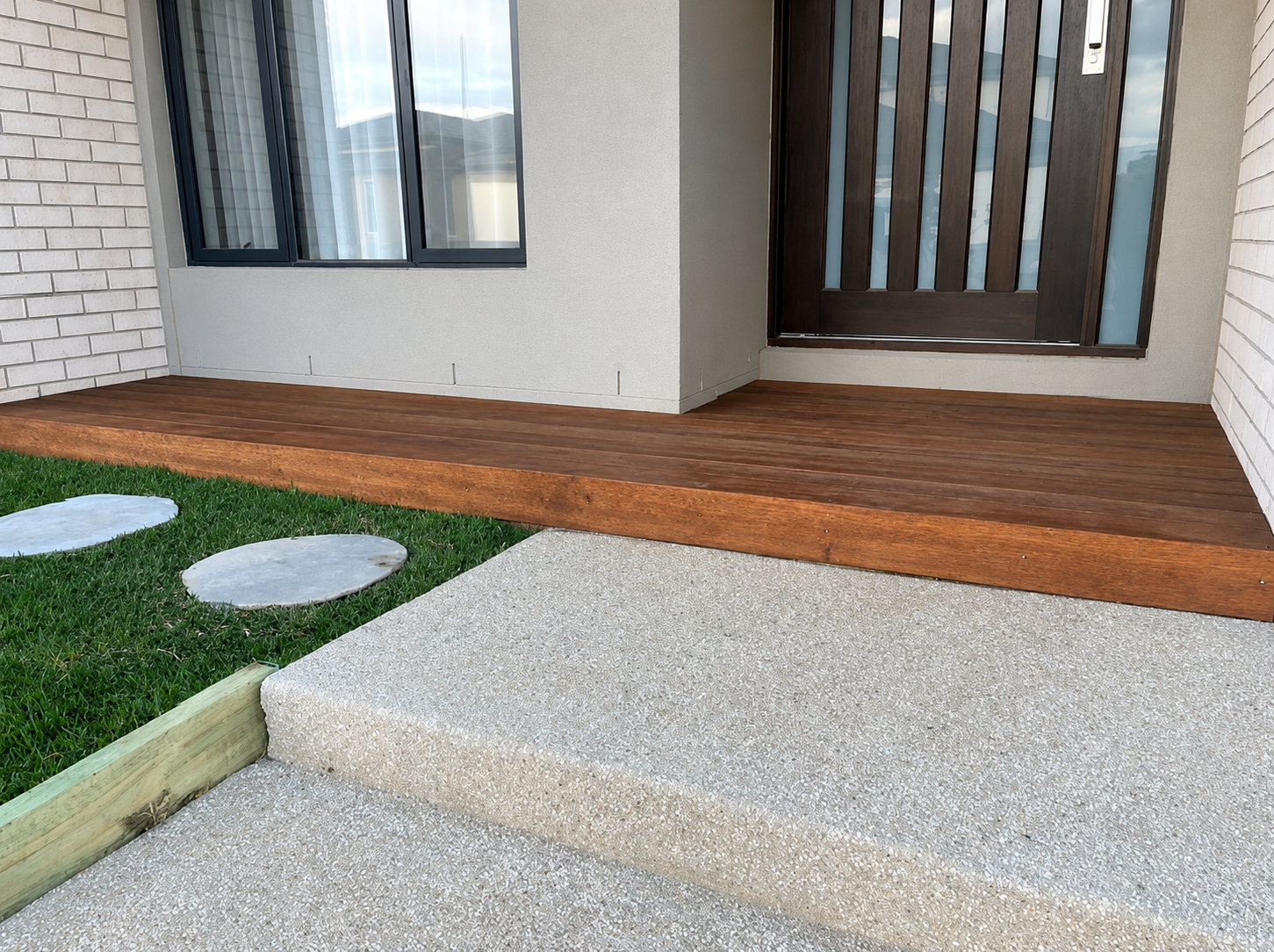 Custom hardwood timber deck at front entrance with exposed aggregate path and lawn stepping stones, Deanside